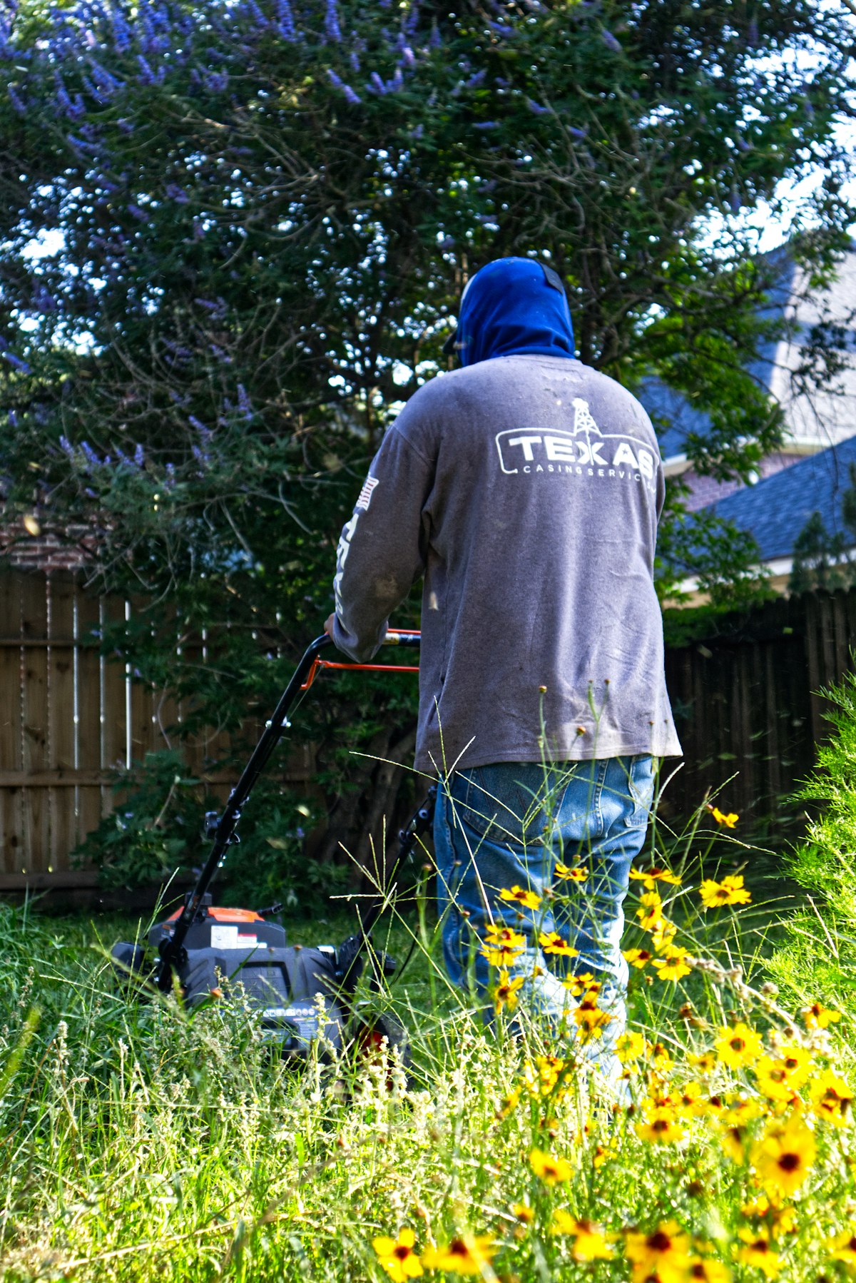 Profissional cortando a grama de um jardim residencial